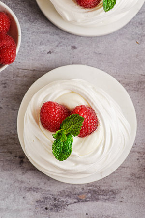 Pavlova meringue dessert with raspberries and cream. The dessert is made from egg whites and powdered sugar, as well as whipped cream. Decorated raspberry and mintの写真素材