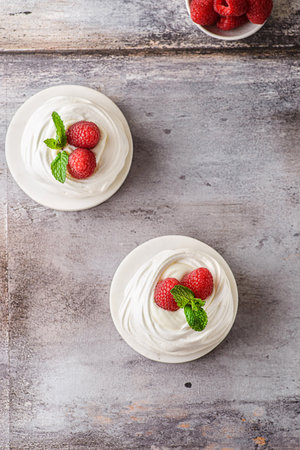 Pavlova meringue dessert with raspberries and cream. The dessert is made from egg whites and powdered sugar, as well as whipped cream. Decorated raspberry and mintの写真素材