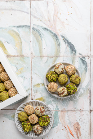 Arabic vegan date energy sqweet balls with pistachios, sesame seeds and almonds in a white boxの写真素材