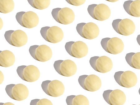 a pattern of chocolates bonbons with white chocolate on a white background with modern harsh lightの写真素材