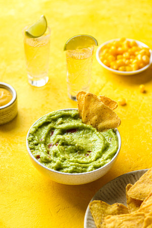 nachos with avocado guacamole on a yellow background. Guacamole is a traditional Mexican snack made from avocado with lime juiceの写真素材