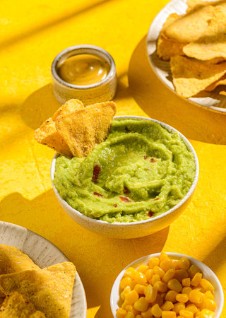 nachos with avocado guacamole on a yellow background. Guacamole is a traditional Mexican snack made from avocado with lime juiceの写真素材