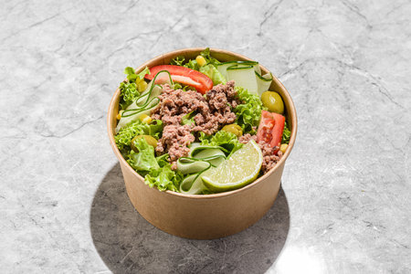 salad with tuna, tomatoes, cucumber and olives in a cardboard container. High quality photoの写真素材