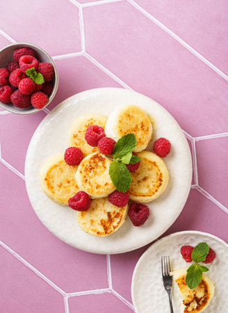 cottage cheese pancakes with raspberries and mint on pink background. High quality photoの写真素材