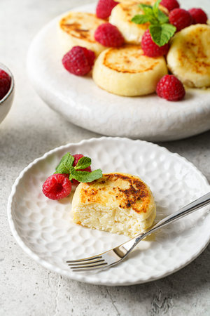 cottage cheese pancakes with raspberries and mint on a light gray background. High quality photoの写真素材