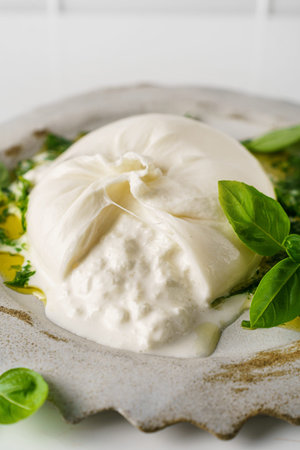 Burrata cheese with basil and olive oil on a white background