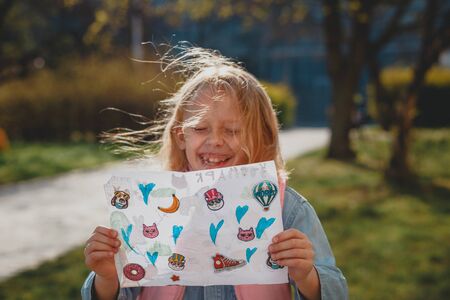 a cute girl with disheveled hair on a Sunny day is laughing and smiling. natural beauty, a delicate girl's face, naturalness, a teenager, a daughter stands on the street in the spring. European child in a blooming Park, the concept of a happy childhoodの写真素材