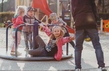a cute European girl with her hair in ponytails is playing on a Playground in a European Park on a Sunny spring dayの写真素材