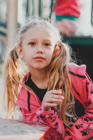 Child with smile on cute face on natural background. Little girl with blond hair ponytails smiling outdoor. Beauty, look, hairstyle. Happy childhood concept.の写真素材