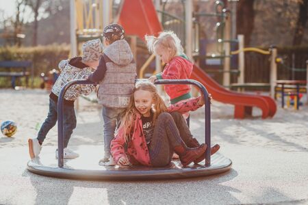 a cute European girl with her hair in ponytails is playing on a Playground in a European Park on a Sunny spring dayの写真素材