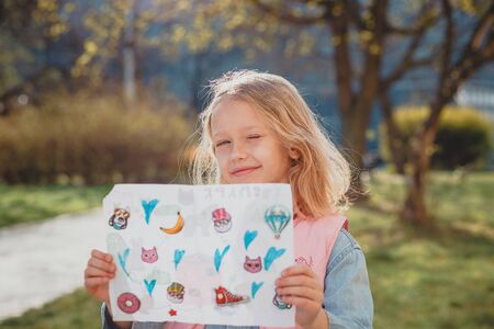 a cute girl with disheveled hair on a Sunny day is laughing and smiling. natural beauty, a delicate girl's face, naturalness, a teenager, a daughter stands on the street in the spring. European child in a blooming Park, the concept of a happy childhoodの写真素材