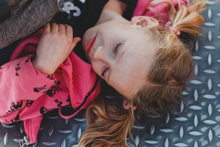 Child with cute face on natural background. Little girl with blond hair ponytails smiling outdoor. Beauty, look, hairstyle. Happy childhood concept.の写真素材