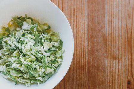 fresh cabbage top view on a wooden table. juicy white cabbage salad on a white plate. copy spaceの写真素材
