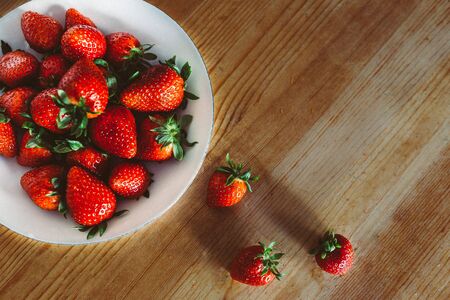 fresh juicy strawberries on a wooden table. organic berry on a white plate. copy spaceの写真素材
