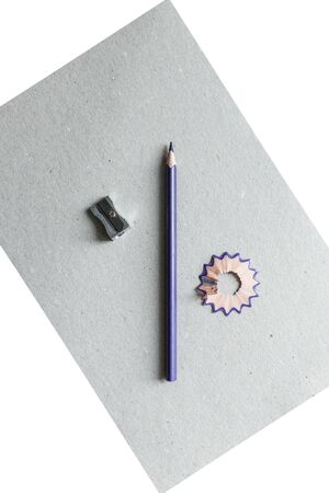 a colored wooden pencil sharpen with a sharpener and shavings lie on a white and gray backgroundの写真素材