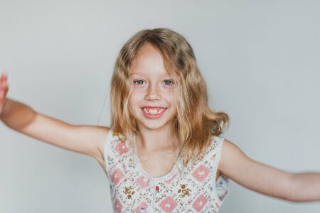 cute European teen girl on a gray background clear skin. beautiful curly blonde with white teeth.の写真素材