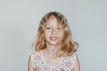 cute European teen girl on a gray background teeth change. beautiful curly blonde with white teeth.の写真素材