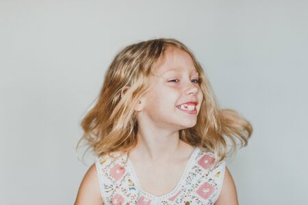 cute European teen girl on a gray background primary teeth. beautiful curly blonde with white teeth.の写真素材