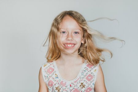 cute european teen girl on a gray background wild hair. beautiful curly blonde with white teeth.の写真素材