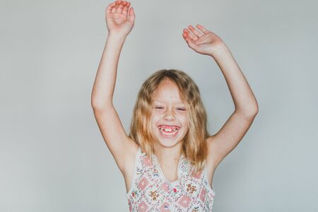 cute european teen girl on a gray background happiness. beautiful curly blonde with white teeth.の写真素材