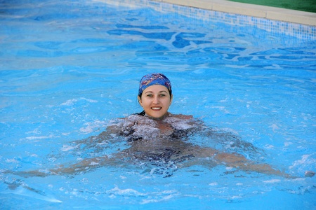 Beautiful young smiling girl sailling in pool in blue kerchiefの写真素材