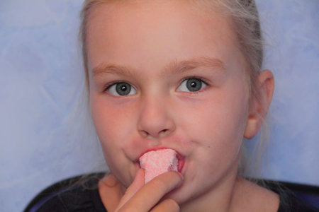 Portrait of beautiful small girl eating sweetmeatの写真素材