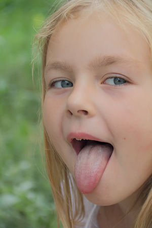 Portrait of small girl with put out tongueの写真素材