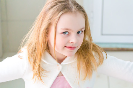 Portrait of cute girl with blond hair in whiteの写真素材