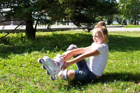Cute girl put on roller skates in summerの写真素材