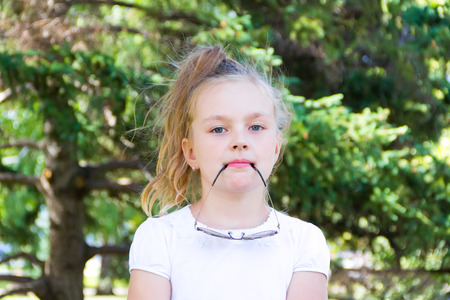 Cute girl playing with sunglasses in summerの写真素材