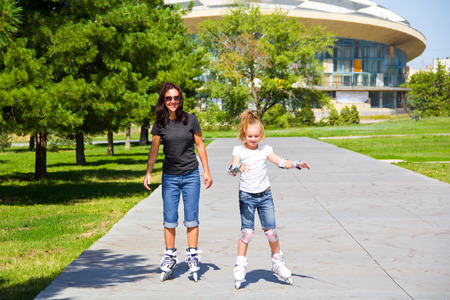 Learning mother and daughter on roller skates in summerの写真素材