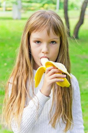 Photo of girl are eating banana in summerの写真素材