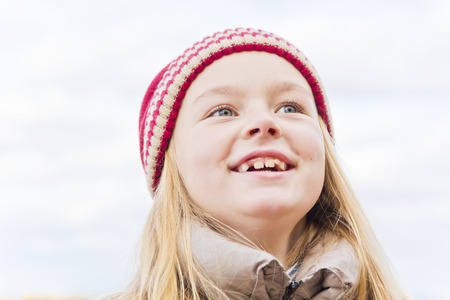 Portrait of cute smiling girl in red hat in autumnの写真素材