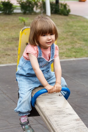 Sad baby riding on hutches at the playground with disheveled hairの写真素材