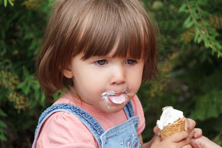 Cute baby girl are eating icecream in summer with put out tongueの写真素材