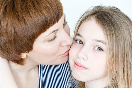 Portrait of kissing mother and daughter on whiteの写真素材