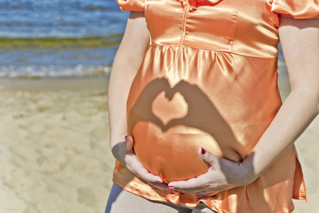 Man hands make heart on wife pregnant stomachの写真素材
