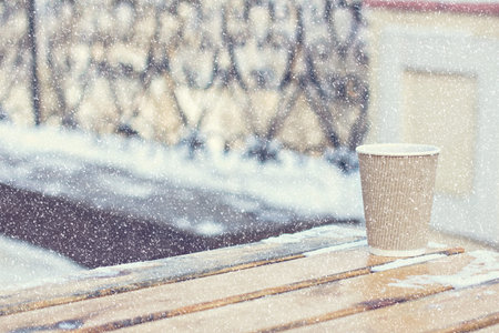 paper craft glass,  cup  with a hot drink, coffee, cocoa, mulled wine and white and black mittens on the table outdoor in the winter. Winter time concept. Bask in the cold.の写真素材