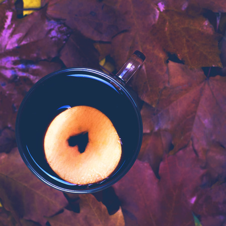 Hot Mulled wine with spices and fruits on an old wooden background. Autumn leaves, nuts, cinnamon. Autumn background. Text space.の写真素材