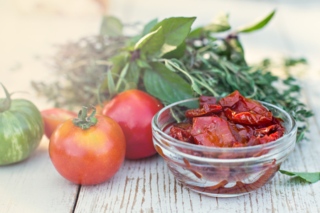Sun dried tomatoes and aromatic herbs - thyme, basil, rosemary. Sun dried tomatoes with herbs and sea salt in olive oil in a glass jarの写真素材
