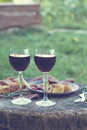 Red wine and light snacks, wine, cheese, pie. Summer romantic dinner in nature. Picnic.の写真素材