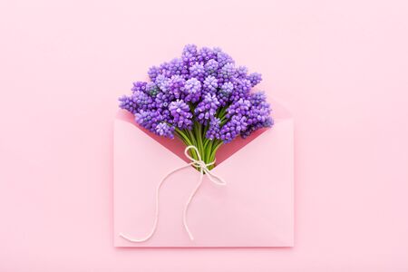 Mothers day message with spring violet flowers in a pink envelope. Birthday, Womens day concept. Flat lay, minimal.の写真素材