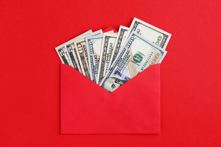 Fan US dollars in cash in red envelope on red background. Money mail concept. Flat lay, minimal style.の写真素材