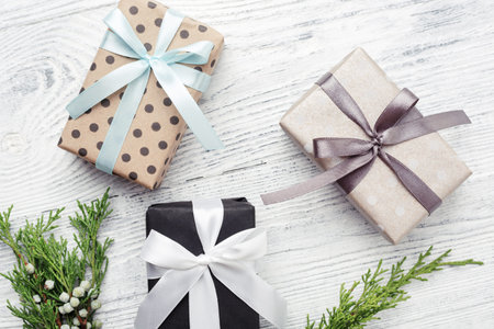 Three gift boxes & green twigs on white wooden background. Christmas, New Year, Boxing day.