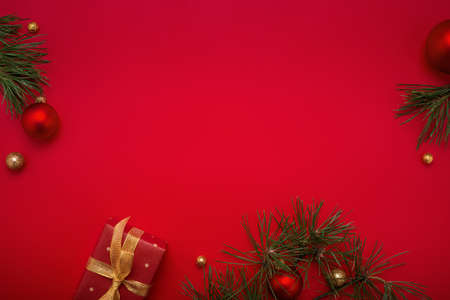 Red Christmas background with gift, green fir tree, gold decorations. Copy space, flat lay.の写真素材