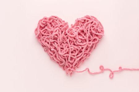 Valentines Day Heart made of yarn on pink background. Love symbol. Copy space, flat lay.