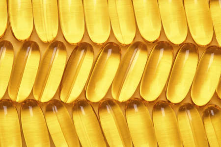 Fish oil softgels in a row, Omega 3 capsules, yellow geometric background.の写真素材