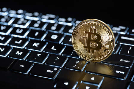 Gold Bitcoin on blue backlit keyboard, crypto currency coin, digital technology conceptの写真素材