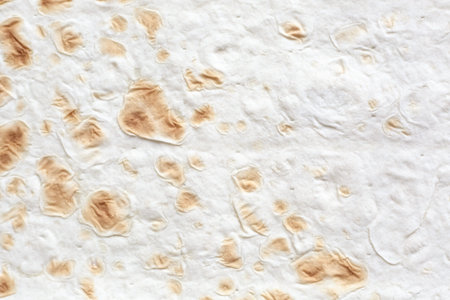 Dough texture of Armenian Lavash bread, natural beige background with golden brown inclusions.