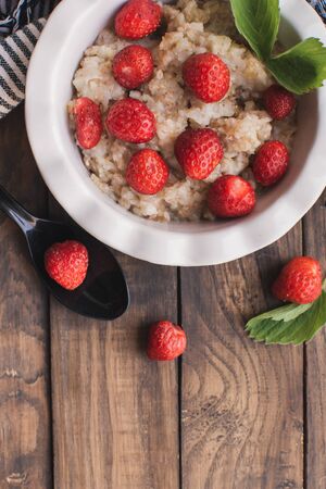 Breakfast. Tasty oatmeal with berries. Healthy breakfast ingredients. Oat granola in bowl with strawberry and mint. Granola for breakfast with berries.の写真素材